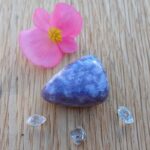 Pink flower beside purple gemstone and clear crystals