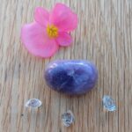 Pink flower, purple stone and clear crystals on wood