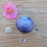 Purple polished crystal sphere with clear crystals and pink flower