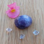 Purple polished stone, clear crystals and pink flower