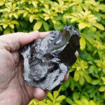 Hand holding shiny black obsidian stone