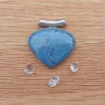 Blue heart-shaped pendant with silver bail on wood