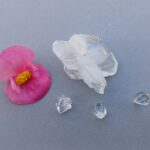 Pink flower with quartz crystals on grey surface