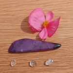 Pink flower and purple stone on wooden surface