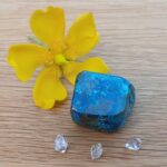 Yellow flower and blue stone on wooden surface