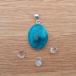Turquoise pendant with silver setting on wooden surface