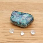 Blue-green polished stone with three clear crystals
