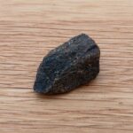 Small dark rock on wooden surface