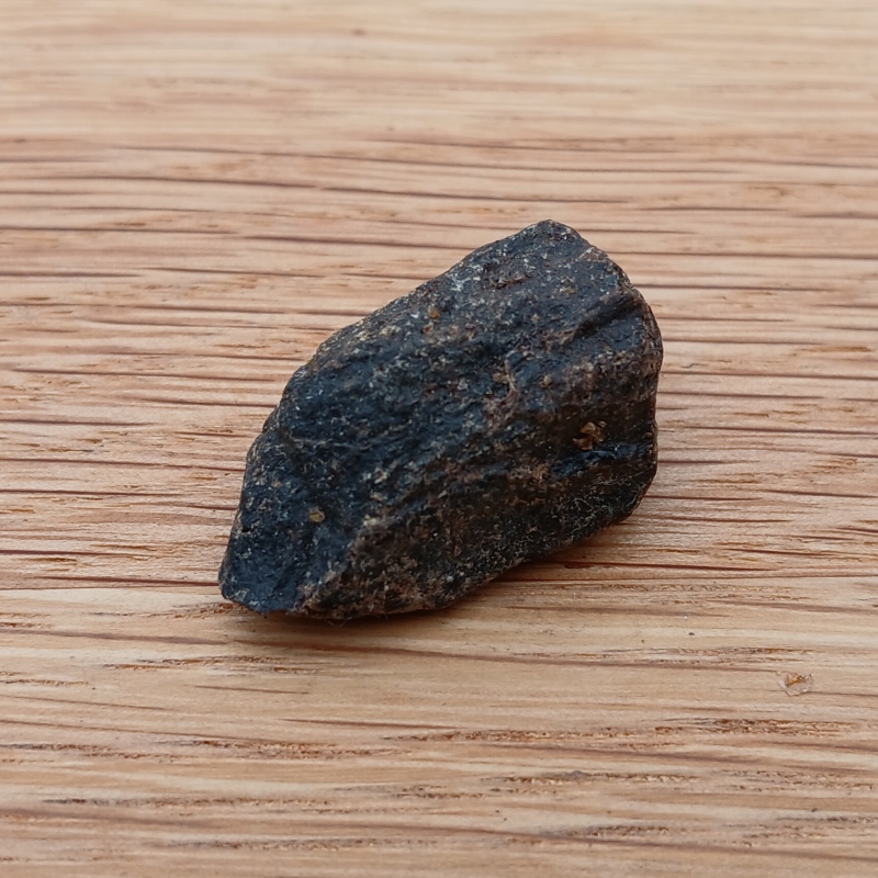 Small dark rock on wooden surface