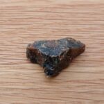 Small dark brown rock on wooden surface