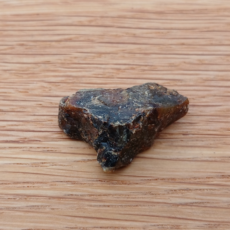 Small dark brown rock on wooden surface