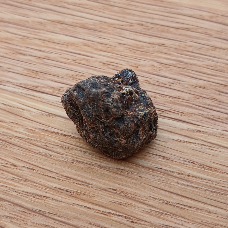 Small rough dark rock on wooden surface