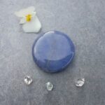 Blue polished gemstone with flower and small crystals