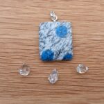 Square blue spotted stone pendant on wooden surface