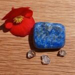 Blue polished stone, red flower and clear crystals