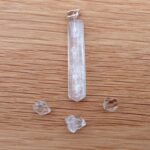 Clear crystal pendant and small stones on wood