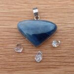 Blue triangular gemstone pendant on wooden surface