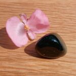 Pink flower beside polished dark green stone