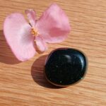 Pink flower beside glittering dark polished stone