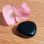 Pink flower beside glittering black polished stone
