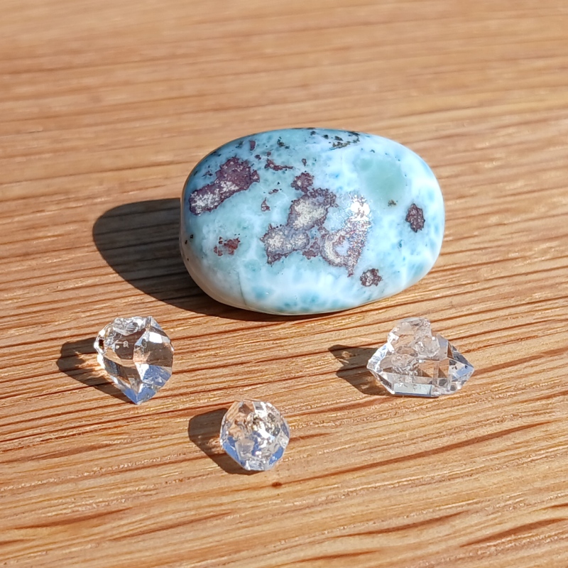 Blue polished stone with clear crystals on wood