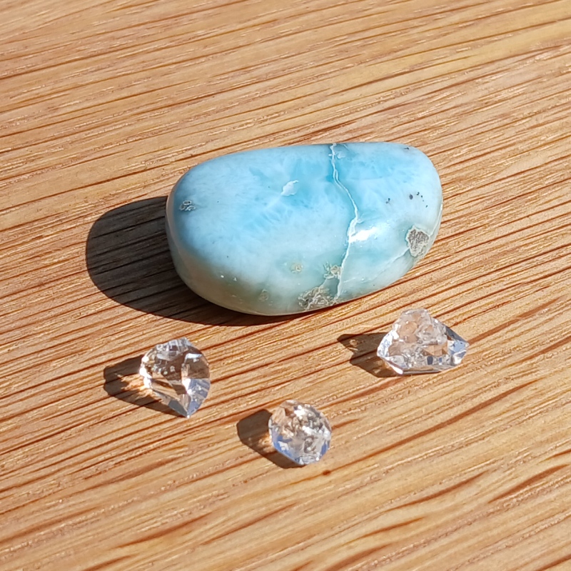 Blue polished stone with clear crystals on wood