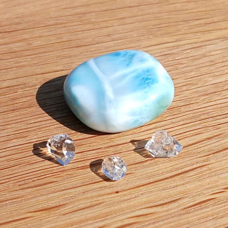 Blue polished stone and clear crystals on wood