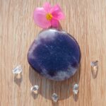 Polished purple stone with pink flower and crystals