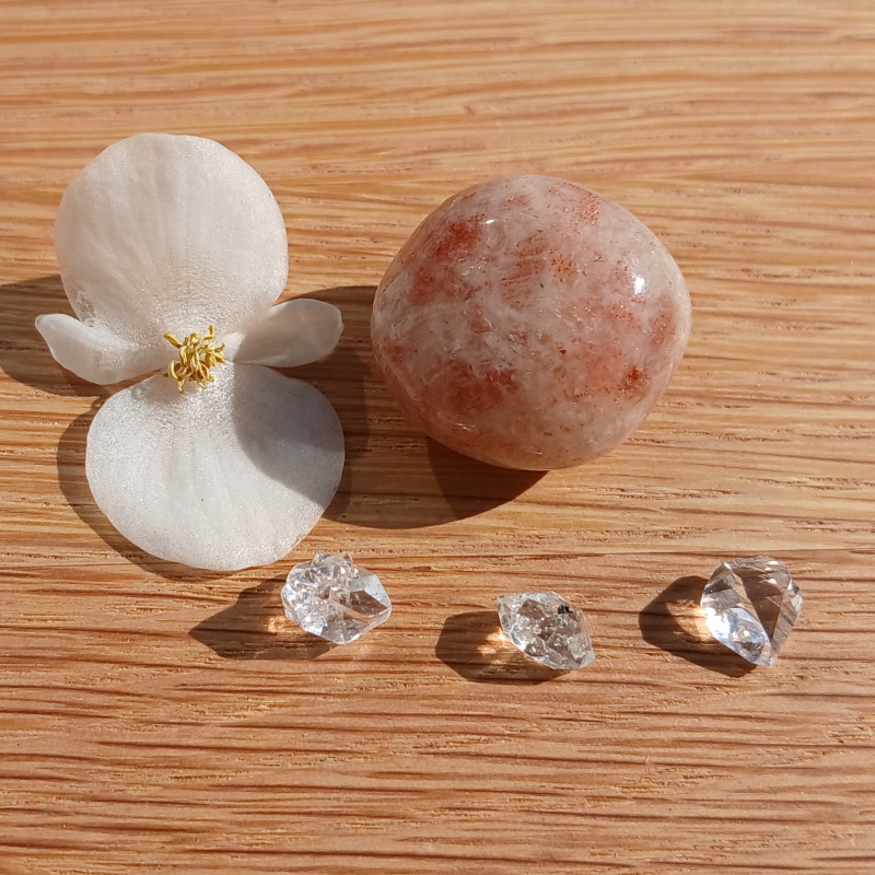 White flower, polished stone and clear crystals on wood