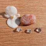 White flower, pink stone and clear crystals on wood