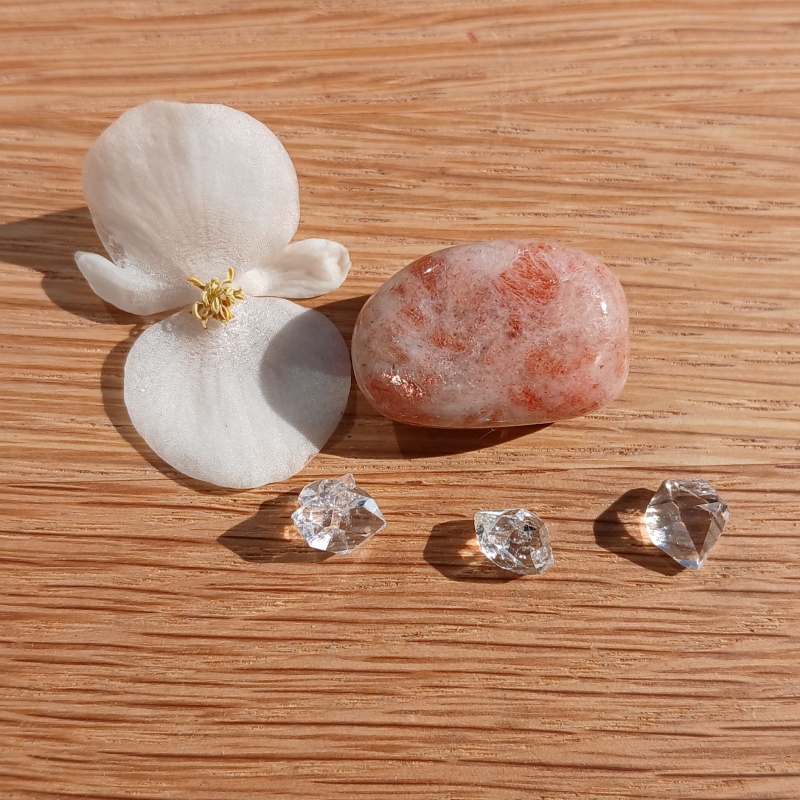 White flower, pink stone and clear crystals on wood