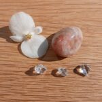 White flower, polished stone and clear crystals on wood
