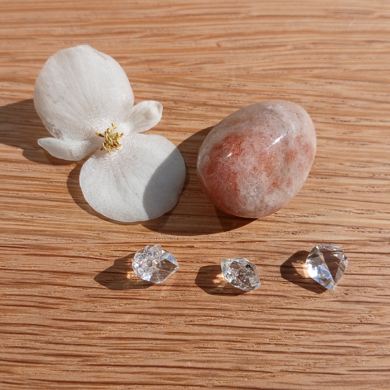 White flower, polished stone and clear crystals on wood