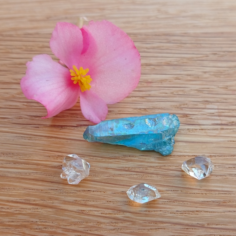 Pink flower beside blue crystal and clear gemstones