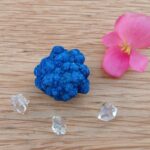 Vivid blue mineral specimen with pink flower and clear crystals