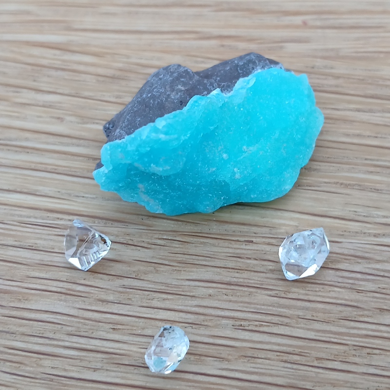 Bright turquoise mineral specimen with clear crystals on wood