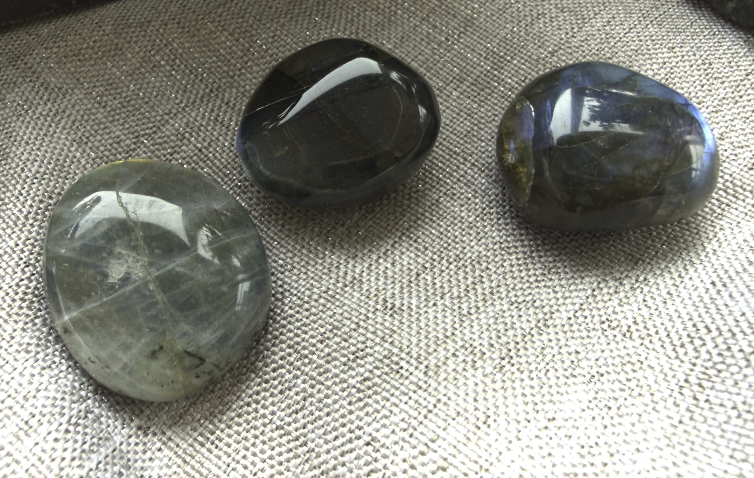 Three polished labradorite stones on textured fabric