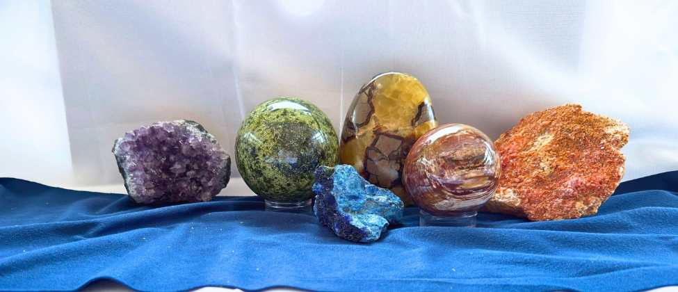 Colourful polished crystal spheres and mineral specimens on blue cloth