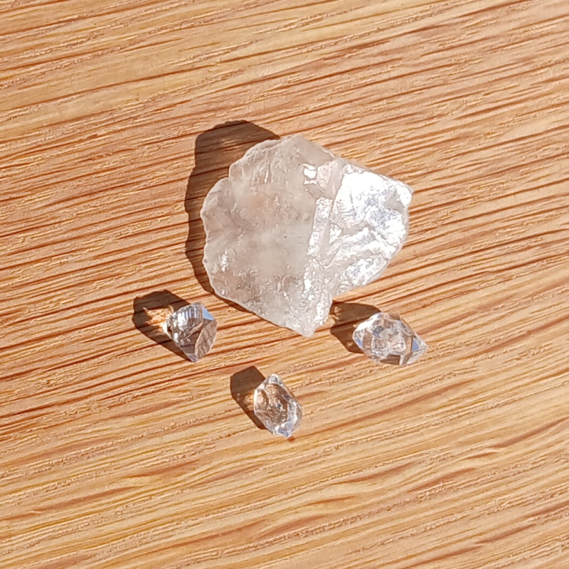 Clear quartz crystals on a sunlit wooden surface