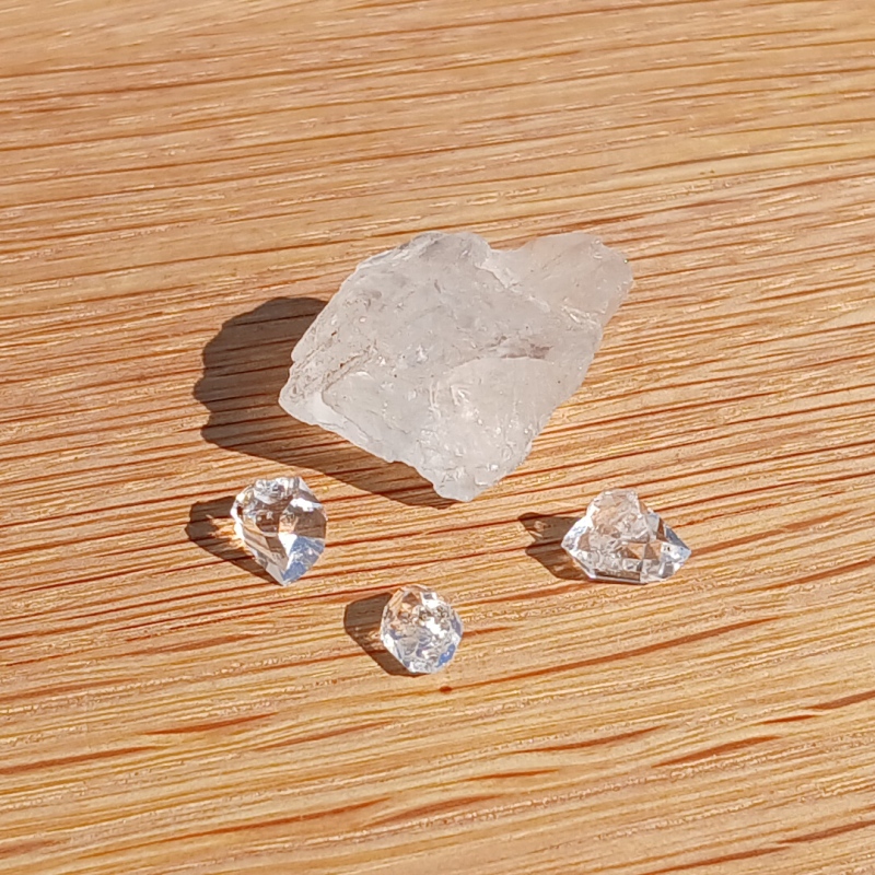 Rough and faceted clear crystals on wooden surface