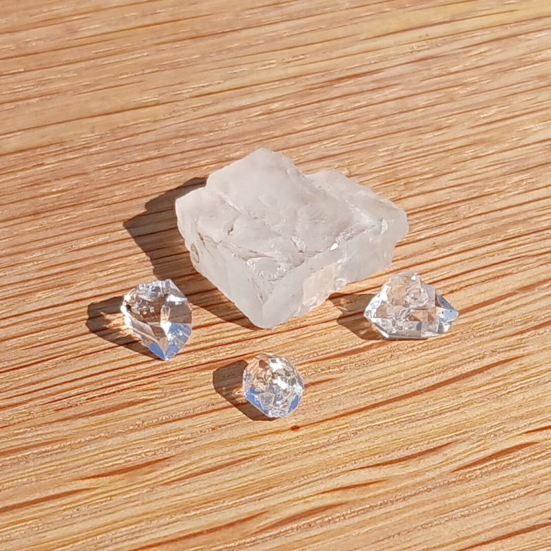 Clear quartz crystals on a sunlit wooden surface