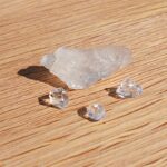 Clear crystals and rough translucent stone on wooden surface