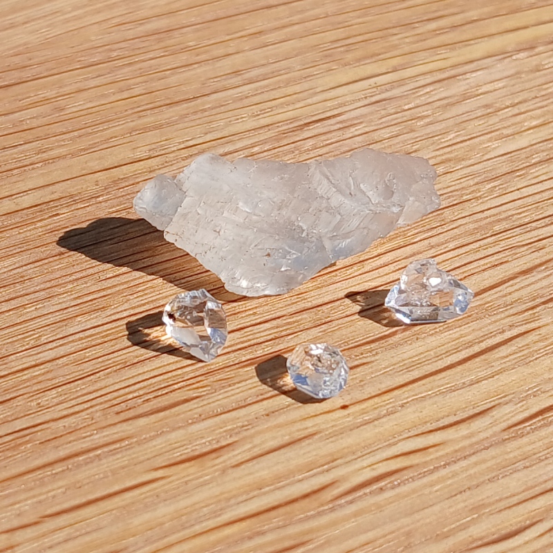 Clear crystals and rough translucent stone on wooden surface