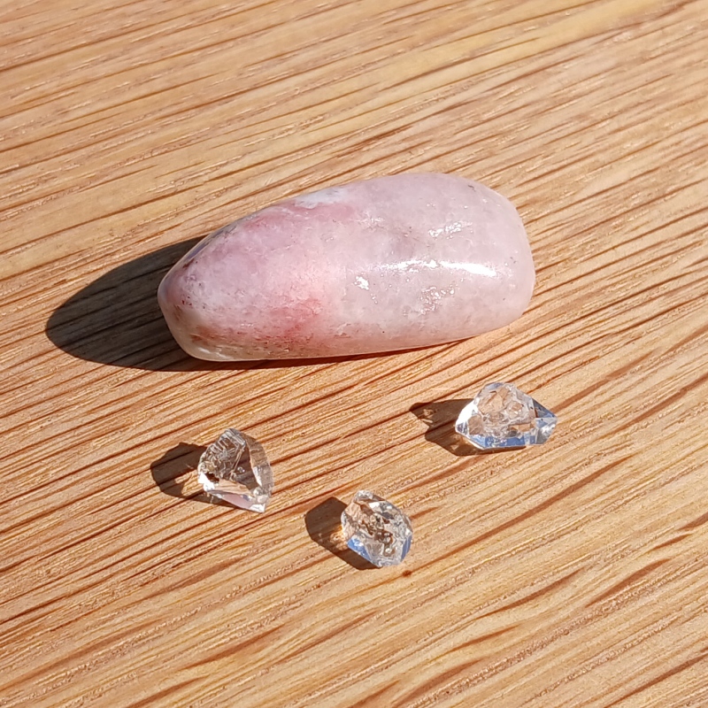 Polished pink stone with three clear crystal fragments