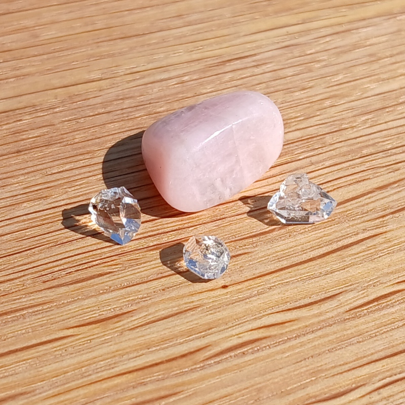 Rose quartz and clear crystals on sunlit wooden surface