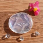 Clear polished crystal with pink flower on wooden surface