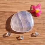 Polished clear crystal with pink flower on wooden surface
