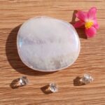 Polished white crystal with pink flower on wooden surface