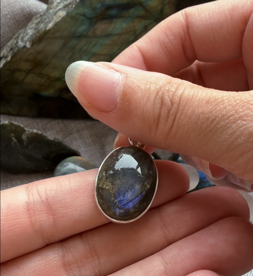 Hand holding silver pendant with blue-flashing labradorite gemstone