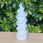 White spiral selenite carving on wooden surface